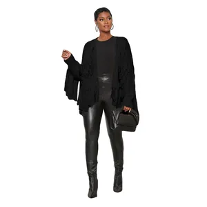 Close-up detail of women's black knitted cardigan with long fringe trim and leather pants