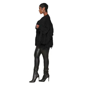 Side view of woman wearing black knitted cardigan with fringe detail and leather leggings