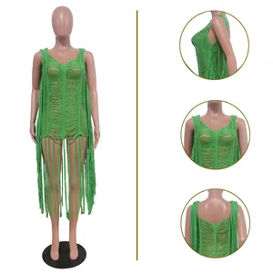 Détail d'une robe de plage verte crochetée à la main avec motifs ajourés et franges.