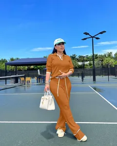 Ensemble deux pièces en maille orange élégant pour femme sur un court de tennis chic.