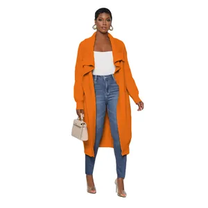 Full body view of a stylish women's orange long knitted cardigan paired with blue jeans