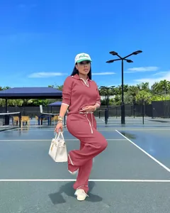 Mannequin en ensemble polo tricoté mauve et pantalon large sur un court de tennis ensoleillé