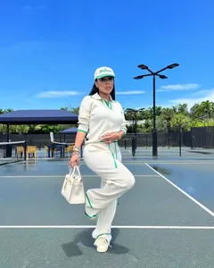 Modèle portant un ensemble en maille crème avec bordure verte sur un court de tennis.