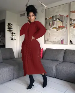 Close-up detail of a red long-sleeved cable-knit sweater dress with fringe trim.