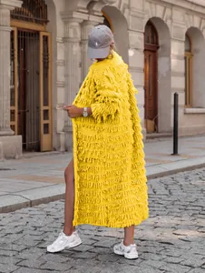 Detailansicht einer hellgelben Strickjacke mit langen Fransen und grober Struktur.