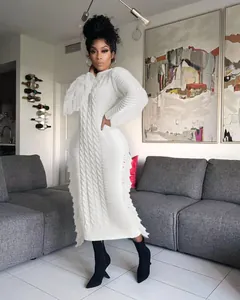 Elegant white cable knit long sweater dress with fringe trim styled on model in home setting
