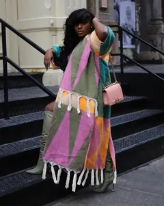 Vue street style d'un gilet en maille patchwork géométrique avec des glands blancs.