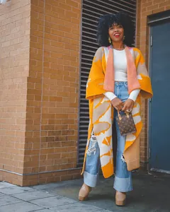 Modell in lebhaftem orange-beige gemustertem langem Strickcardigan im Freien