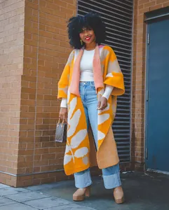 Ganzkörperaufnahme eines schicken langen Damen-Strickcardigans mit orangefarbenem Blattmuster