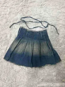 Detalle de falda plisada vaquera lavada vintage con un acabado azul degradado único