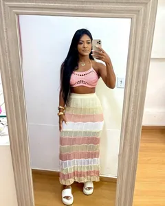 Foto de cuerpo entero de modelo con top de ganchillo rosa y falda de playa de punto a rayas