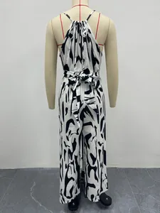 Back view of a black and white milk print halter wide-leg jumpsuit with a waist tie