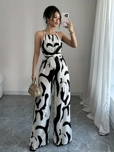 Elegant black and white milk print halter wide-leg jumpsuit shown in a modern interior.
