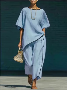 Mannequin portant un ensemble deux pièces bleu clair effet lin avec liseré noir.