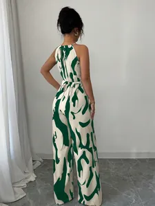 Back view of a chic green and white abstract print halter wide-leg jumpsuit with waist tie