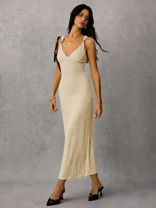 Full body shot of an elegant beige ribbed v-neck maxi dress with gold strap details.