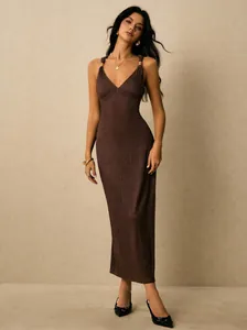 Elegant detail of a brown ribbed midi bodycon dress featuring gold ring strap accents.