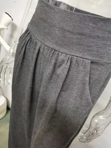 Close-up of high-waisted wide-leg grey yoga pants with pleated details and side pocket.