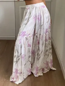 Détail d'un pantalon large à fleurs taille haute avec des volants étagés et un tissu fluide.