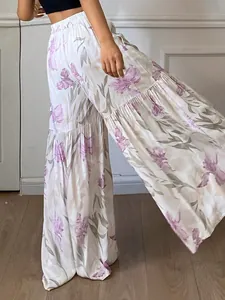 Gros plan montrant le drapé fluide et le motif floral violet de ce pantalon large taille haute.