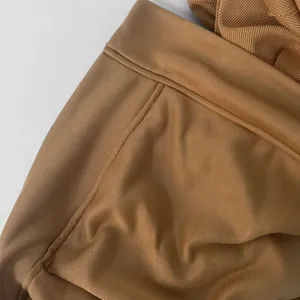 Detail shot of fine stitching and fabric texture on a camel brown hooded jacket.