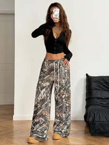 Vrouw in trendy camouflagebroek met wijde pijpen en een modieuze zwarte crop top.
