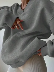 Detailed texture shot of a grey oversized V-neck sweatshirt with ribbed cuffs and hem.