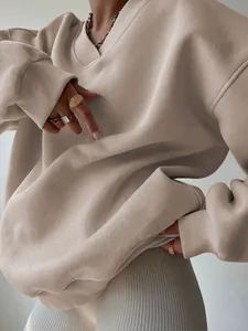 Close-up detail of a beige oversized V-neck sweatshirt with soft knit fabric texture