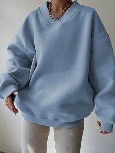 Detail view of a dusty blue oversized sweatshirt with V-neck and ribbed cuffs.