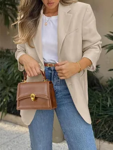 Detailed view of a beige British style casual blazer for women with a brown handbag