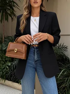 Chic black oversized blazer styled with blue jeans and a brown leather handbag.