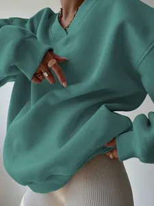 Detailed shot of oversized teal sweatshirt showing ribbed cuffs and soft cotton fabric