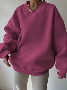 Macro view of oversized fuchsia V-neck sweatshirt featuring ribbed cuffs and soft texture.