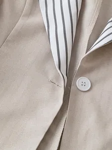 Close-up detail of women's khaki blazer with a striped contrast lapel and white button.