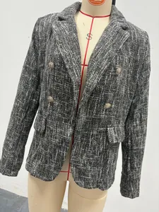 Close-up of black and white tweed blazer with double-breasted gold buttons and flap pockets.