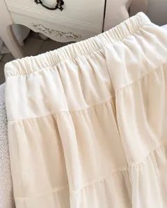 Detail shot of the elastic waist and delicate tiered fabric on this white French maxi skirt.