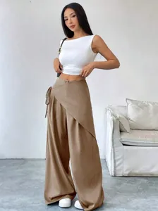 Asian model wearing a white crop top and brown irregular wide-leg trousers in a minimalist room