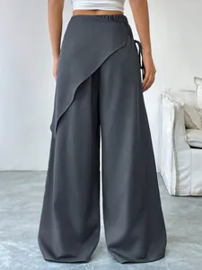 Detail of dark gray wide-leg suit pants featuring an irregular wrap-around back design.
