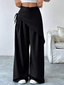 Detail shot of irregular high-waisted black wide-leg suit trousers for women