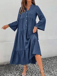 Detailed view of a blue V-neck tiered dress with bell sleeves and button accents