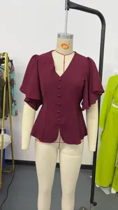 Vista dettagliata del top bordeaux con scollo a V e bottoni su manichino da sartoria.