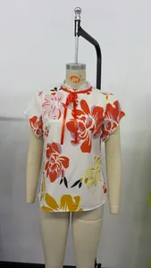 Detail view of floral print blouse with ruffle neck and orange ribbon tie on mannequin