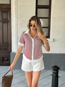 Close-up lifestyle view of a woman wearing a striped polo shirt and white shorts