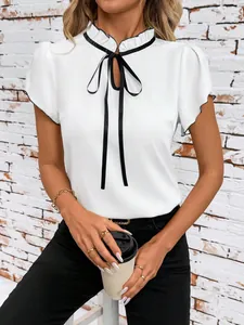Detailed view of elegant ruffled collar and black bow tie on white short-sleeve blouse.