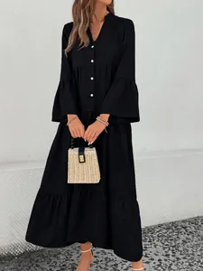 Detailed view of a black V-neck A-line dress with flared sleeves and straw bag