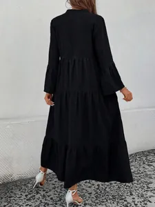 Back view of a black tiered maxi dress with flared sleeves and textured fabric detail.