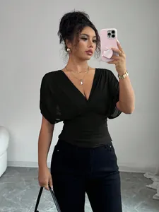 Detailed shot of a black short sleeve top featuring a deep V-neck and ruched waist