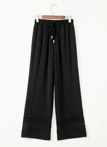 Close-up detail of black high-waisted wide-leg pants with wooden beads and lace