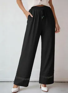 Detailed view of black high-waisted wide-leg trousers with elegant lace hollow-out hem