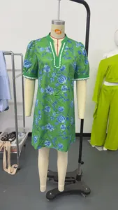 Close-up detail of a green floral resort style dress with scalloped V-neck trim